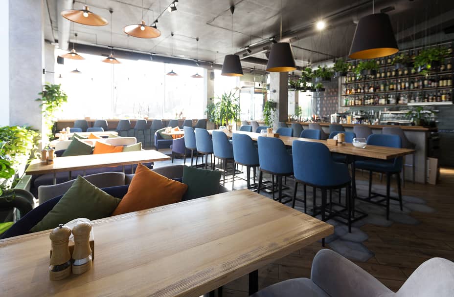 木製テーブルとカラフルなクッションが並ぶおしゃれなカフェ店内